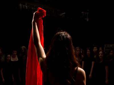 A person standing with their back to the camera holding up a red cloth