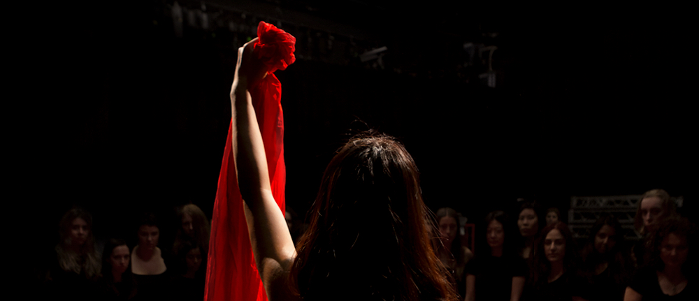 A person standing with their back to the camera holding up a red cloth