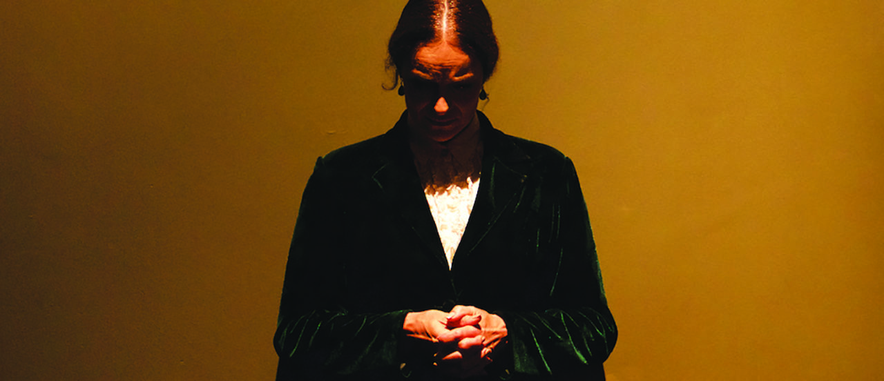a woman clasping her hands looking down