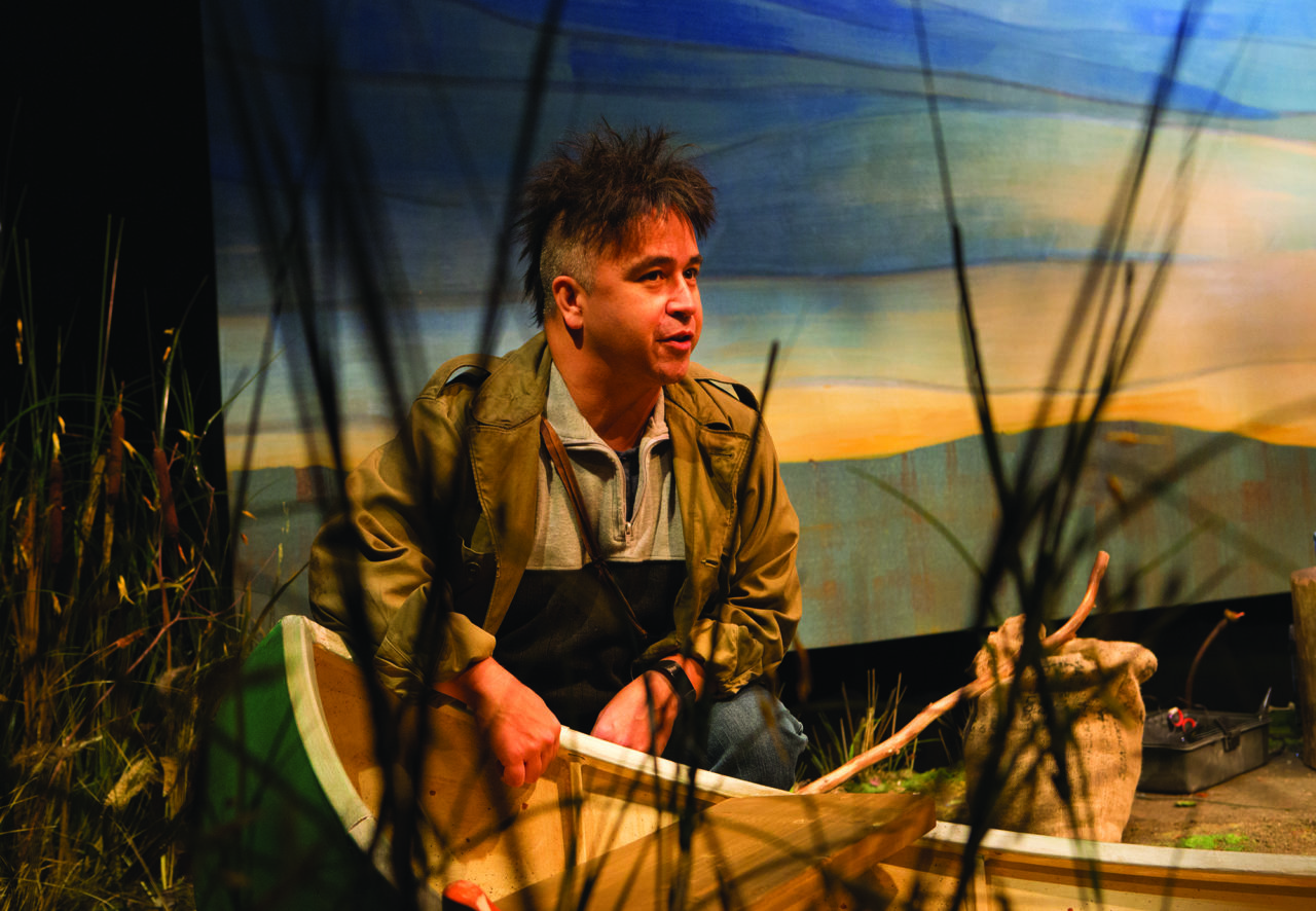 a man sits in a boat amongst reeds