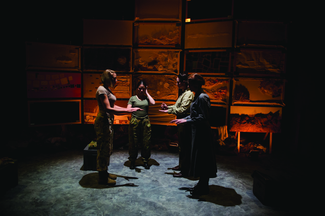 four women dressed in army clothes stand together in a semi-circle