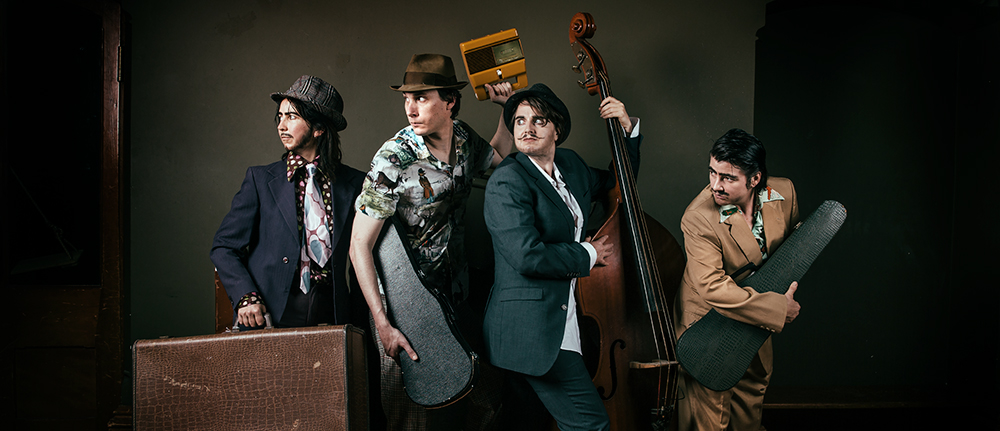Four people with instruments in masc drag