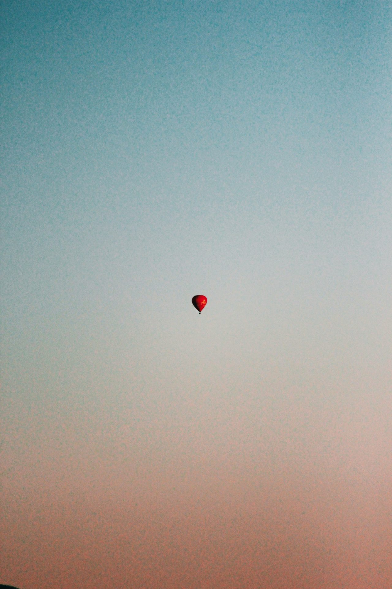 A red ballon high in a sunset sky