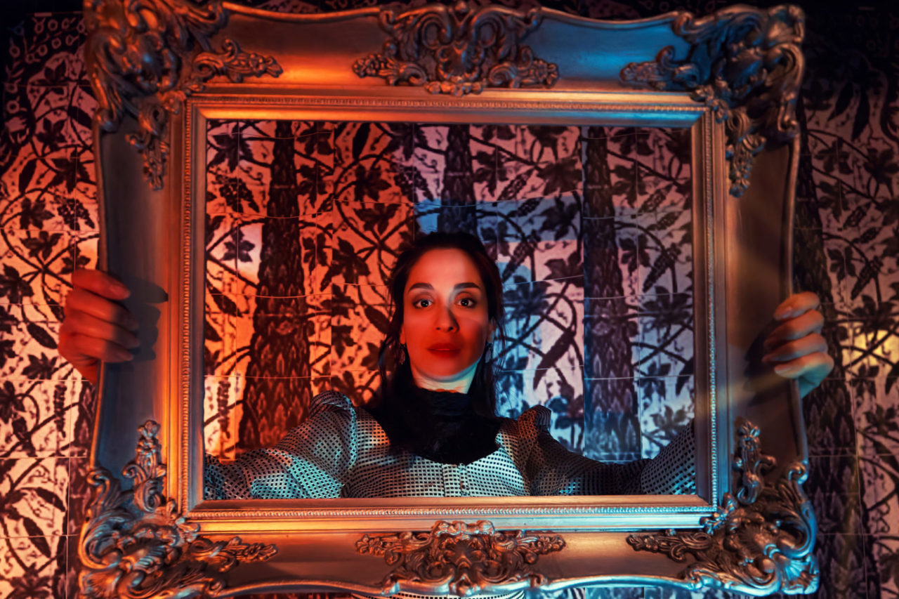 A woman holds a picture frame around her face