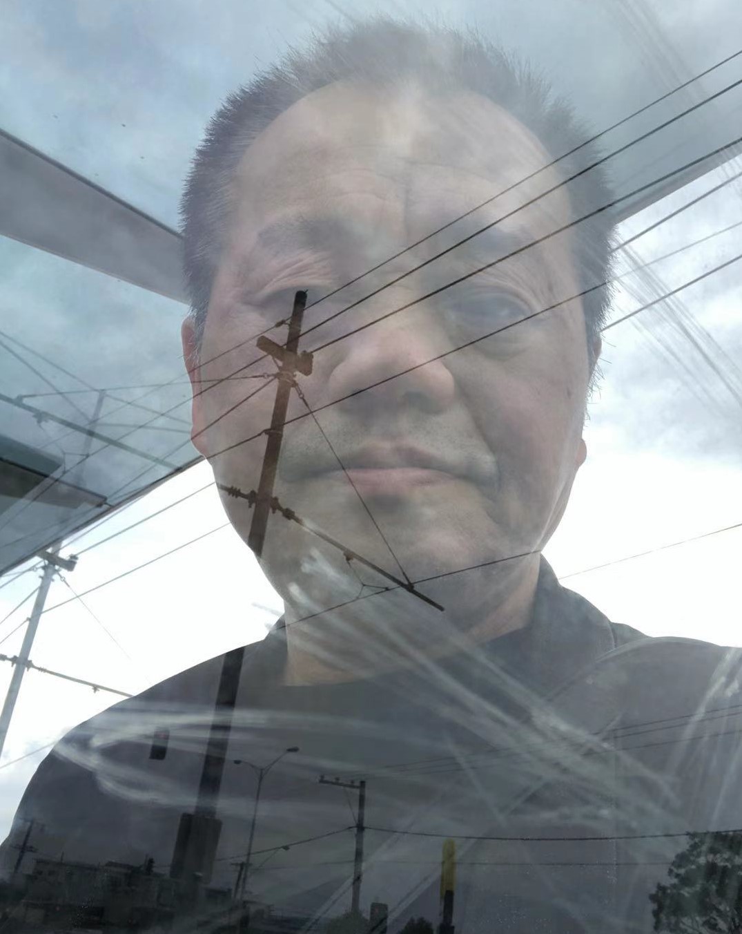 An image of a man from Chinese background overlayed over an image of the sky and powerlines.