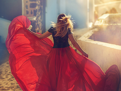 Woman in red dress walking cobbled streets of a Greek island