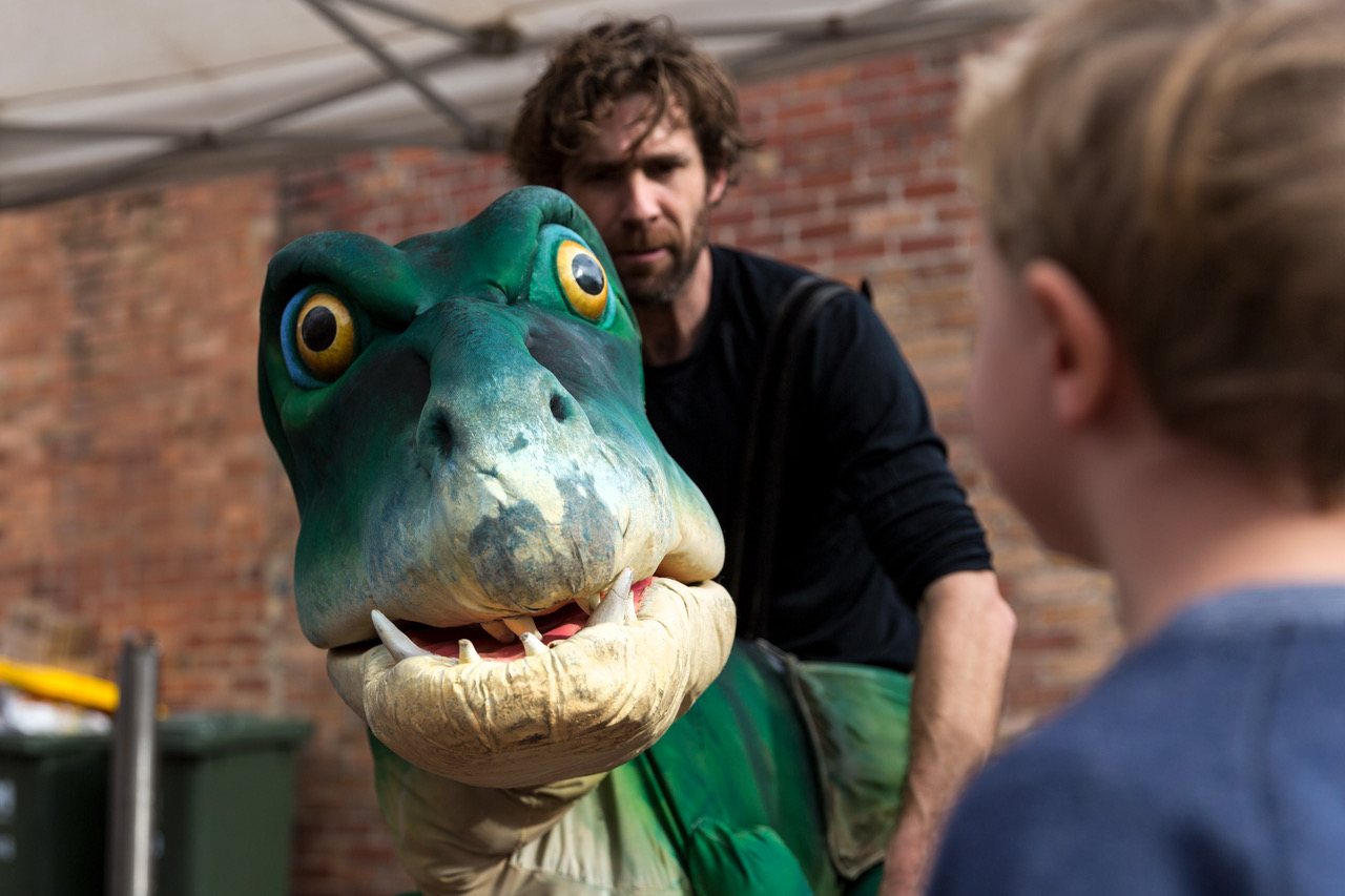 a man with a dino puppet the back of a child