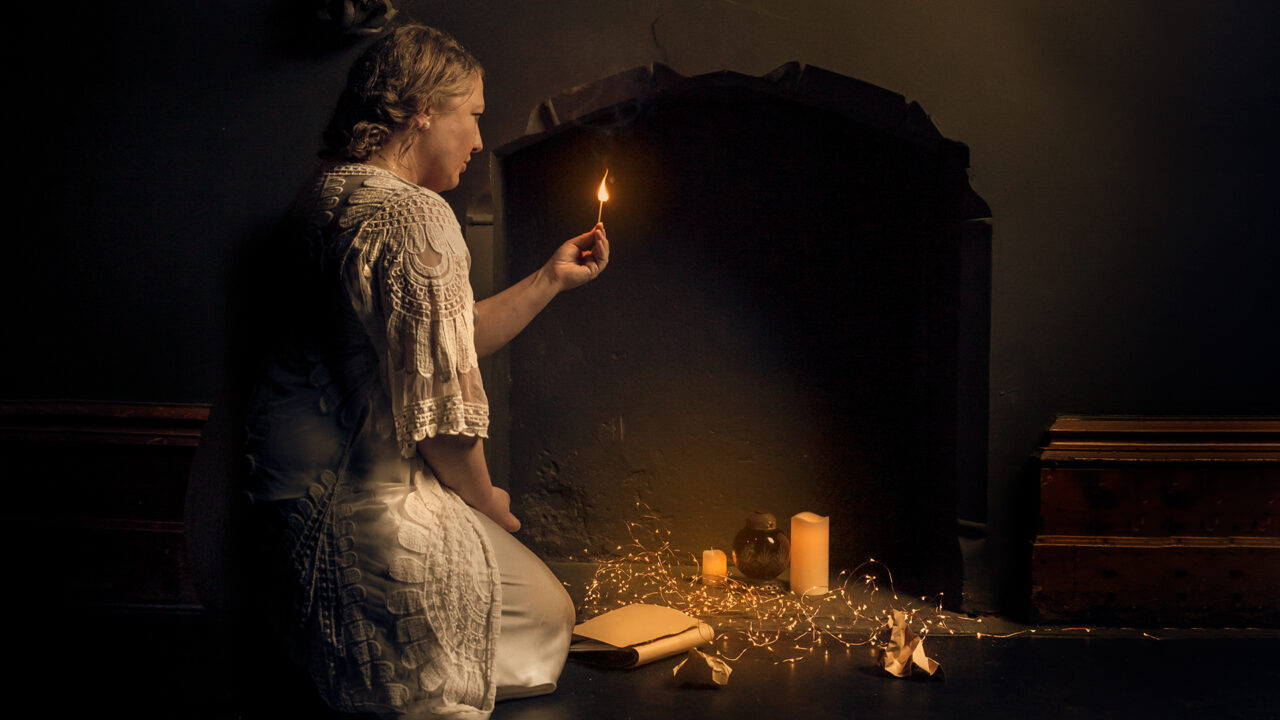An outline of a female lighting a match next to a fire place.
