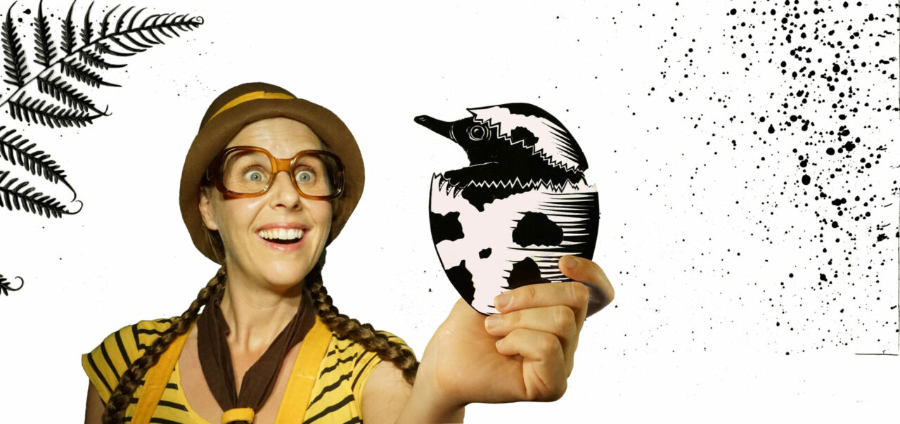 An excited girl scout holds an egg with a baby echidna inside, in her hand
