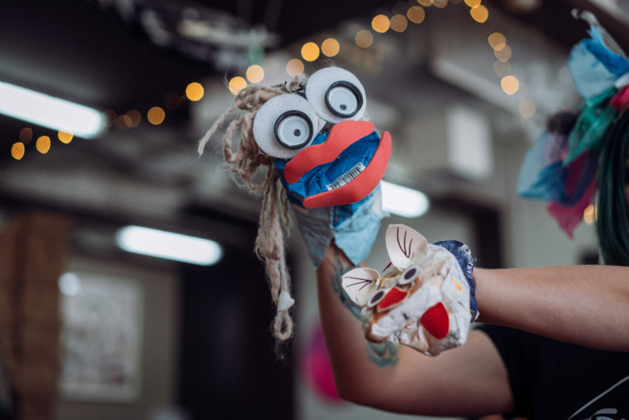 A hand held puppet with a cute face made out of rubbish