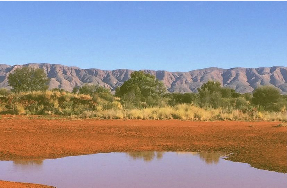 a desert mountain range with a body of water in front.