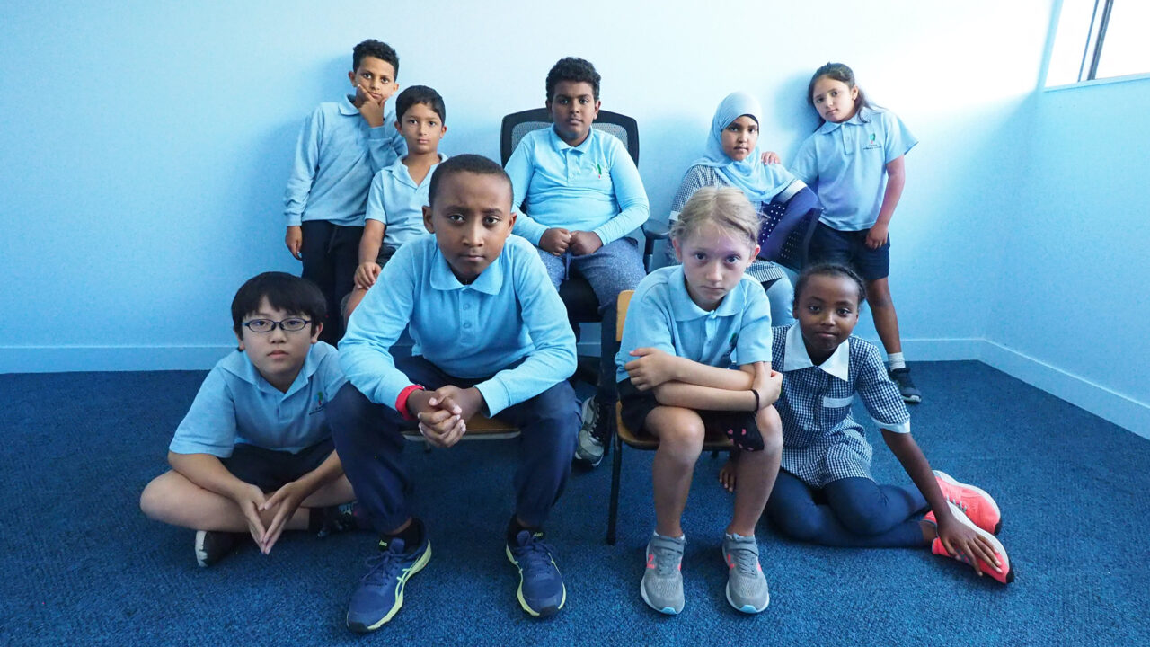 A group of young people from Carlton Primary School look directly into the camera.