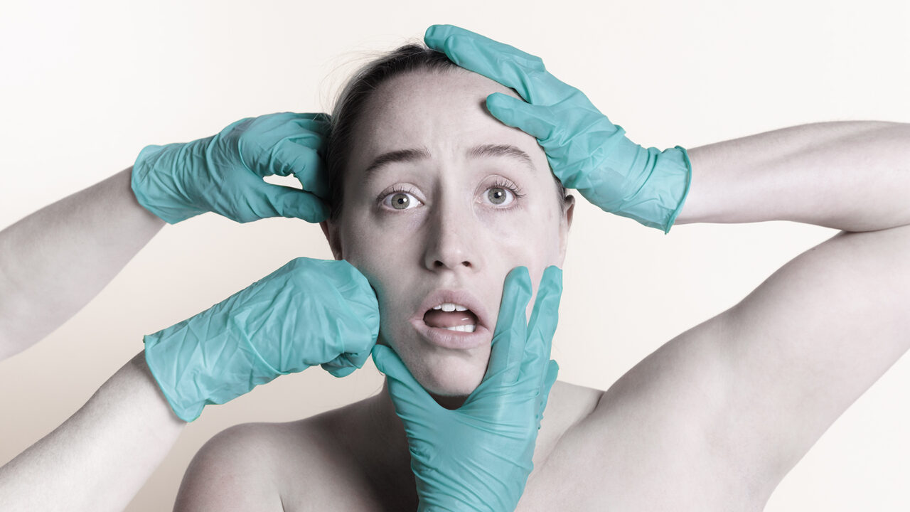 a woman is grabbed at from all angles by gloved hands.